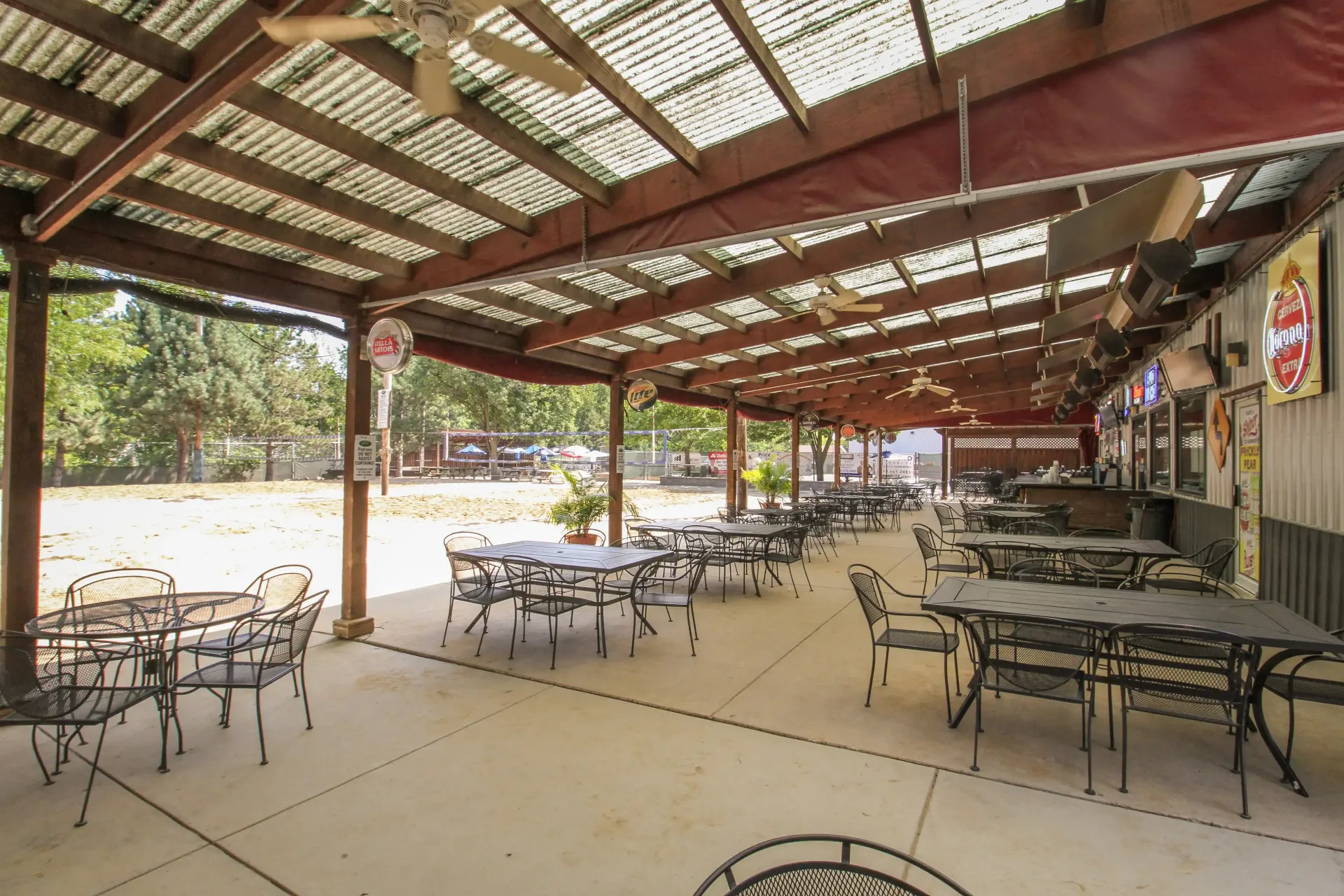 A restaurant with tables and chairs under a covered patio.