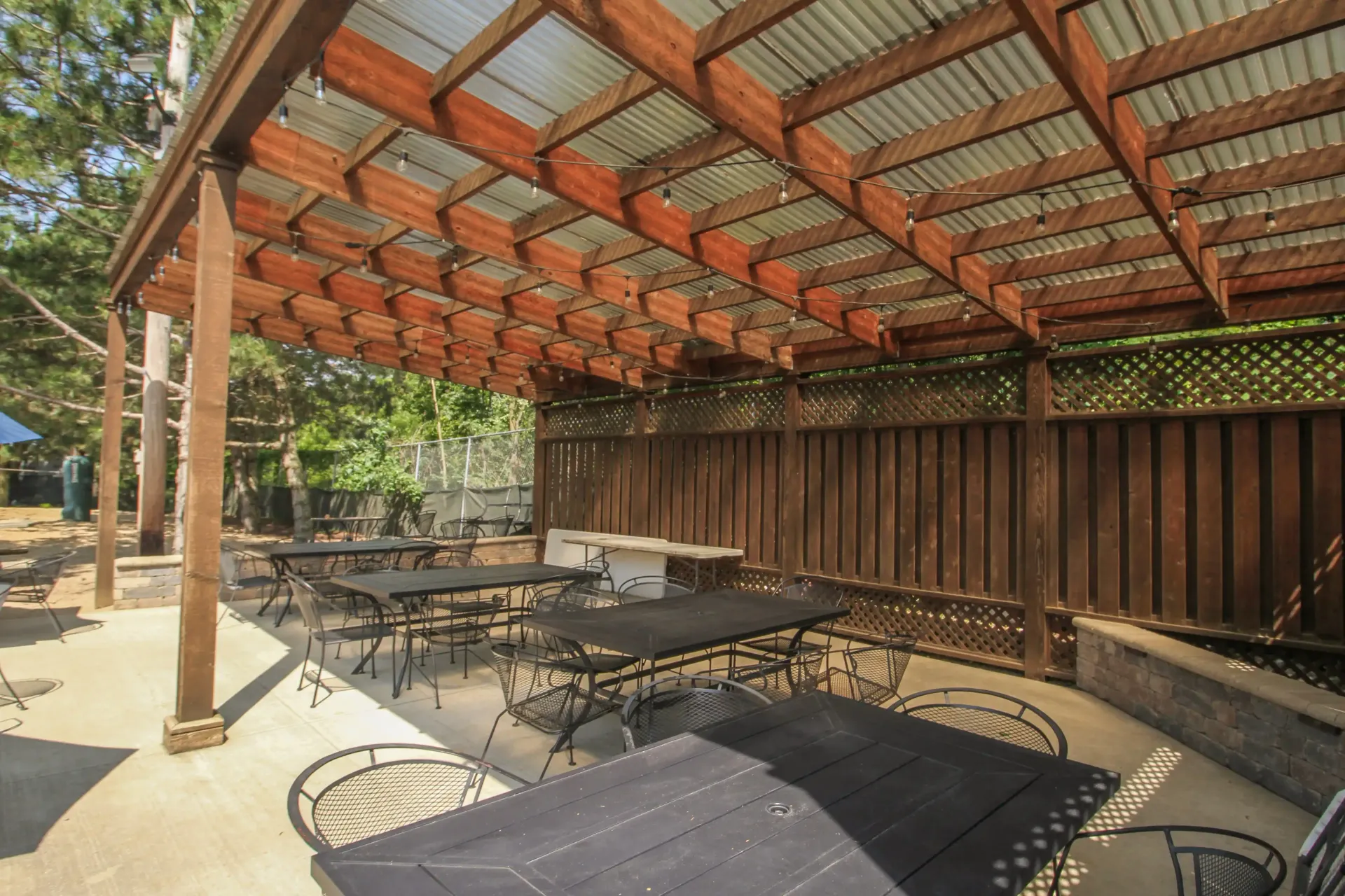 A patio with tables and chairs under a wooden pergola.