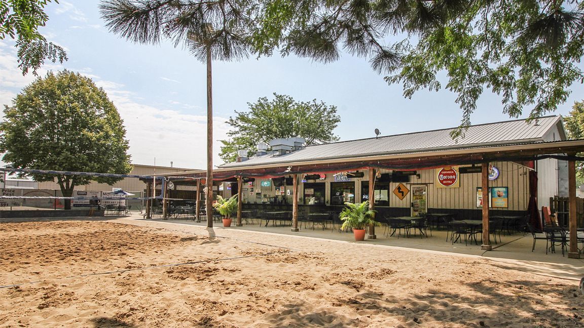 A restaurant with a large volleyball court area in front of it.