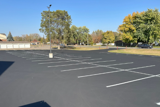 An empty parking lot with trees in the background
