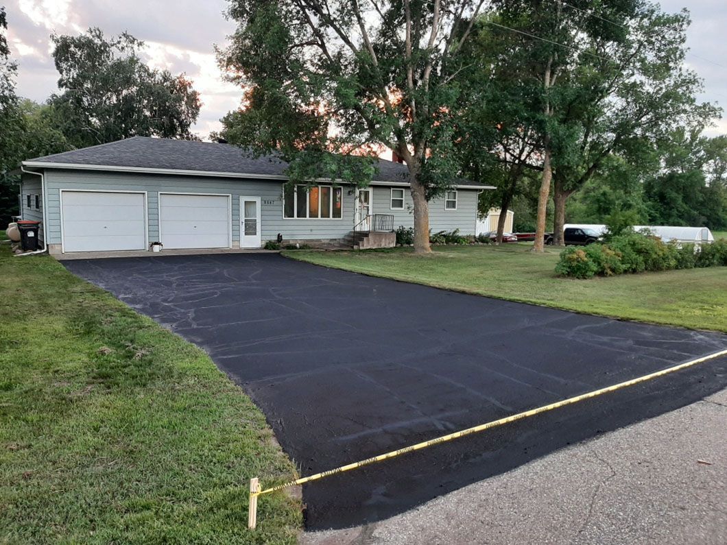 A white house with a black driveway in front of it.
