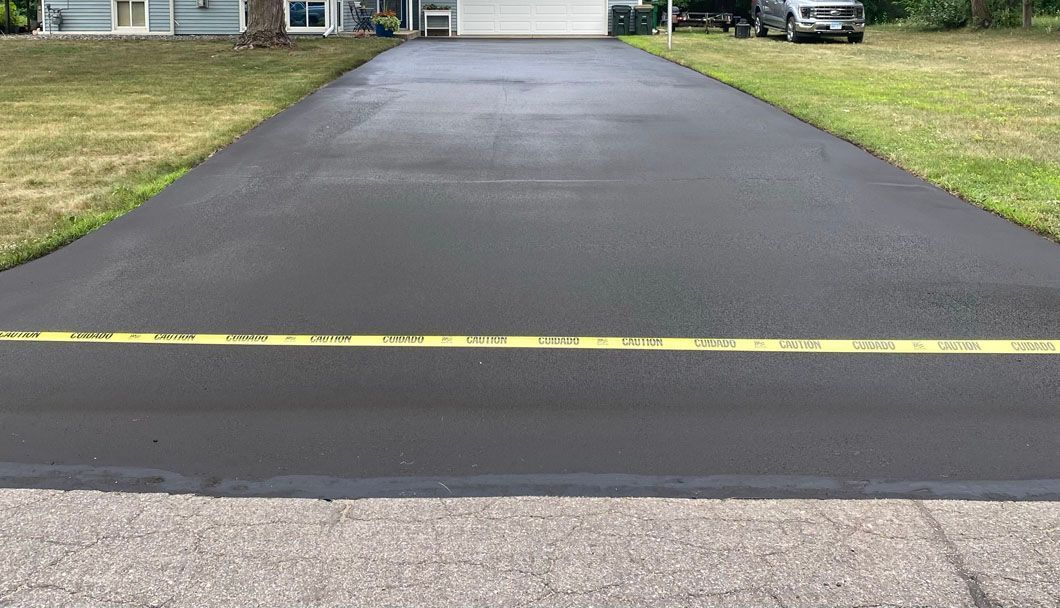 A driveway with a yellow line on the side of it is leading to a house.