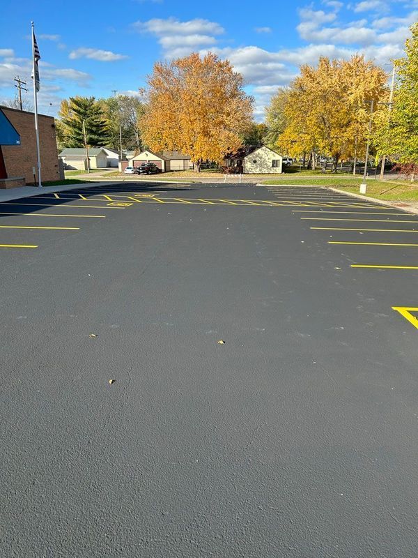 A parking lot with yellow lines and trees in the background