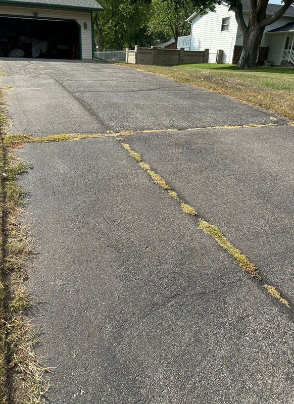 A concrete driveway with a yellow line on the side of it leading to a garage.