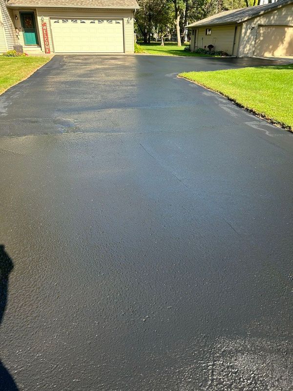 A very clean asphalt driveway in front of a house.