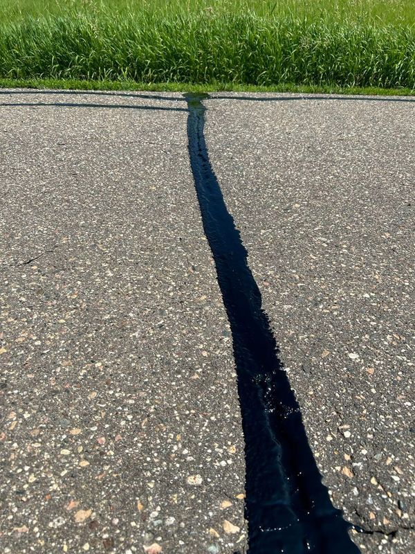 A shadow of a person is cast on the asphalt of a road.