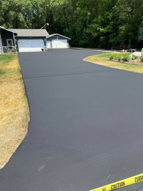 A black asphalt driveway leading to a house.