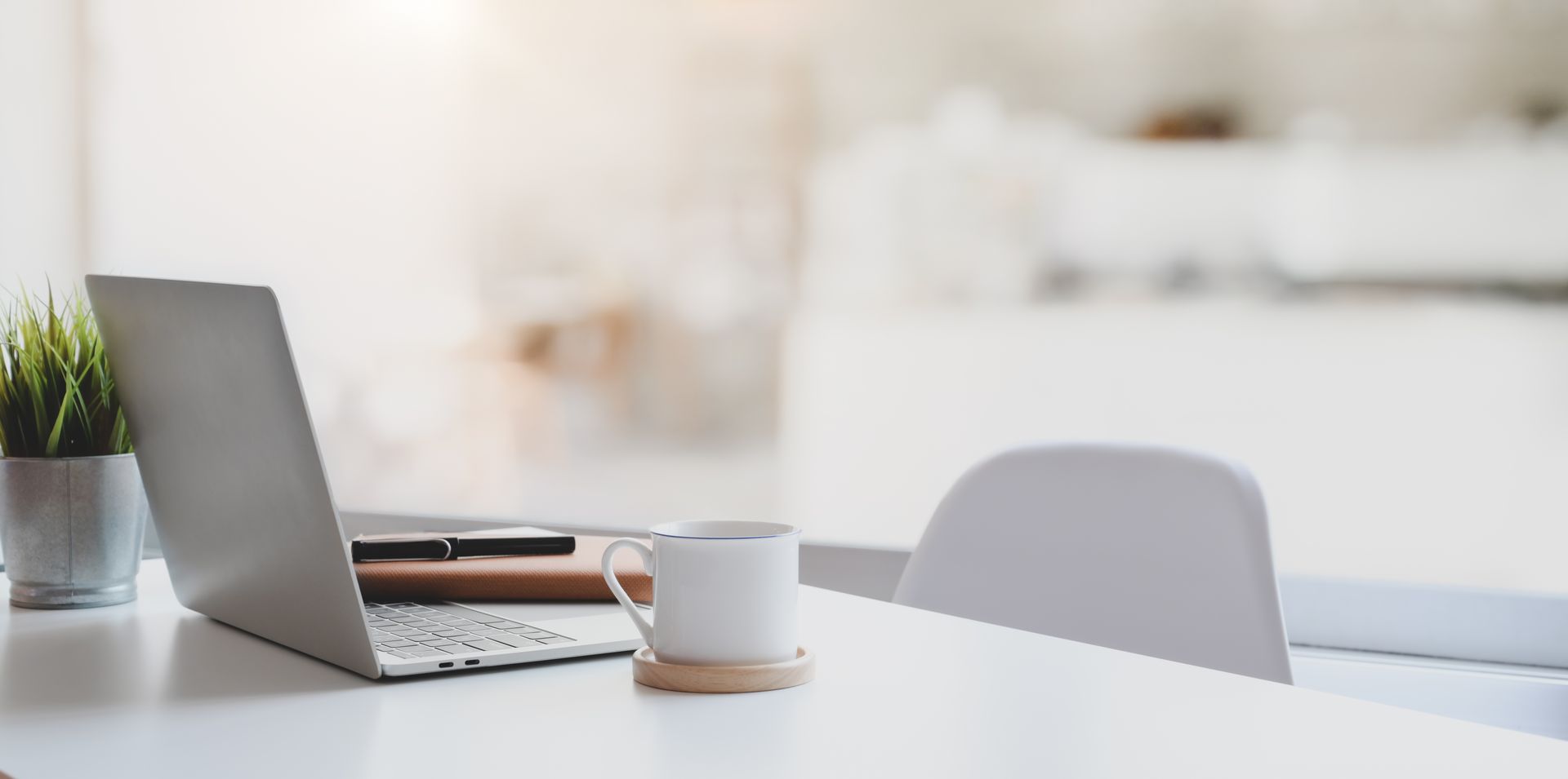 A laptop computer is sitting on a white table next to a cup of coffee.
