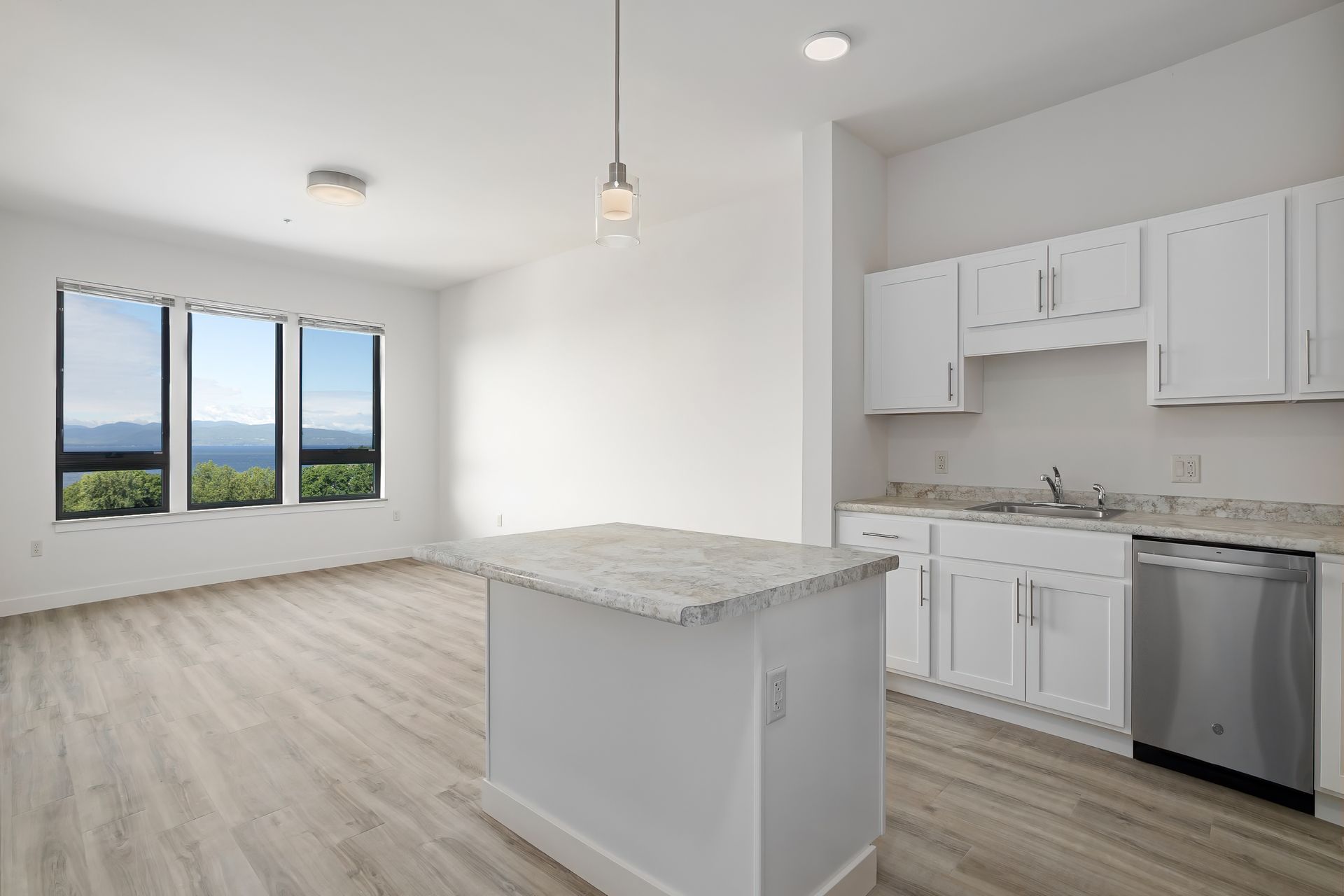 A kitchen with white cabinets and stainless steel appliances and a large island in the middle of the room.