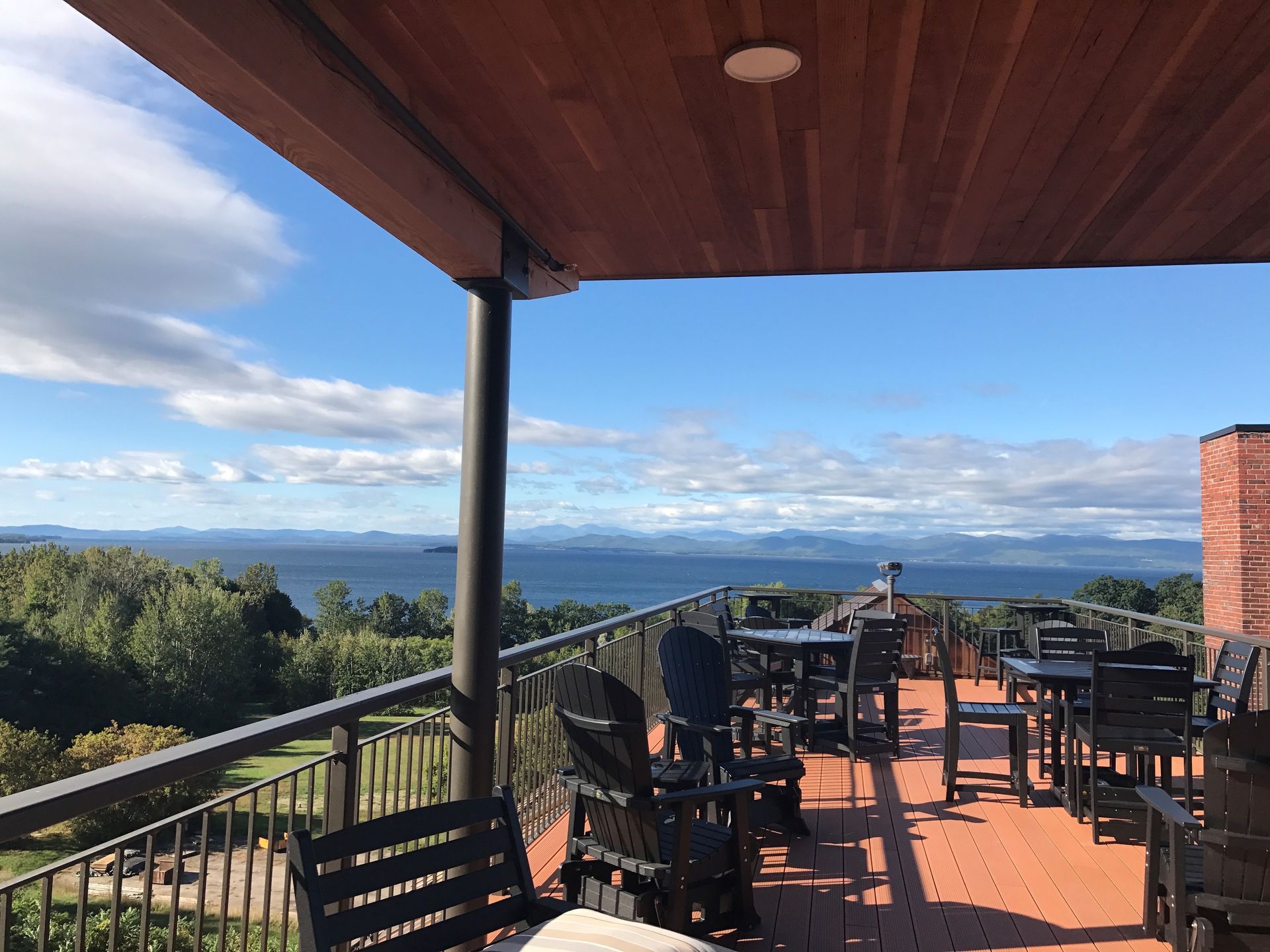 A balcony with tables and chairs overlooking the ocean
