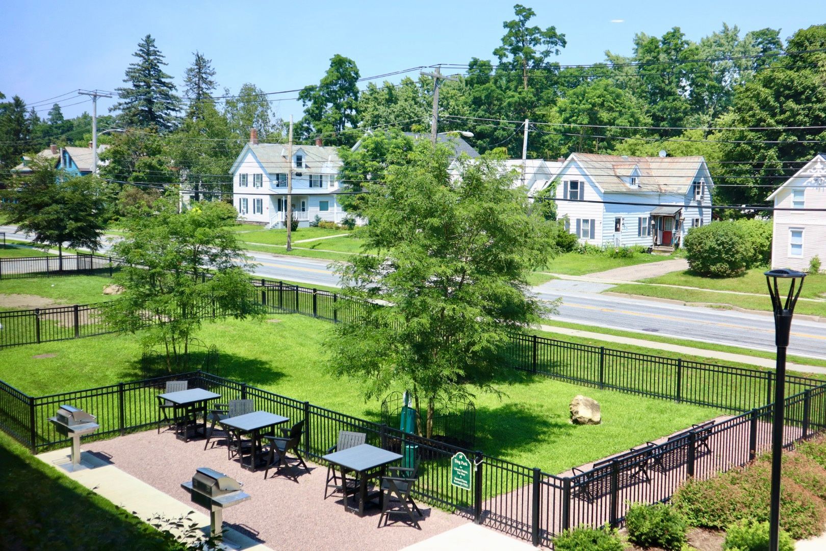 A fenced in area with tables and chairs in the grass