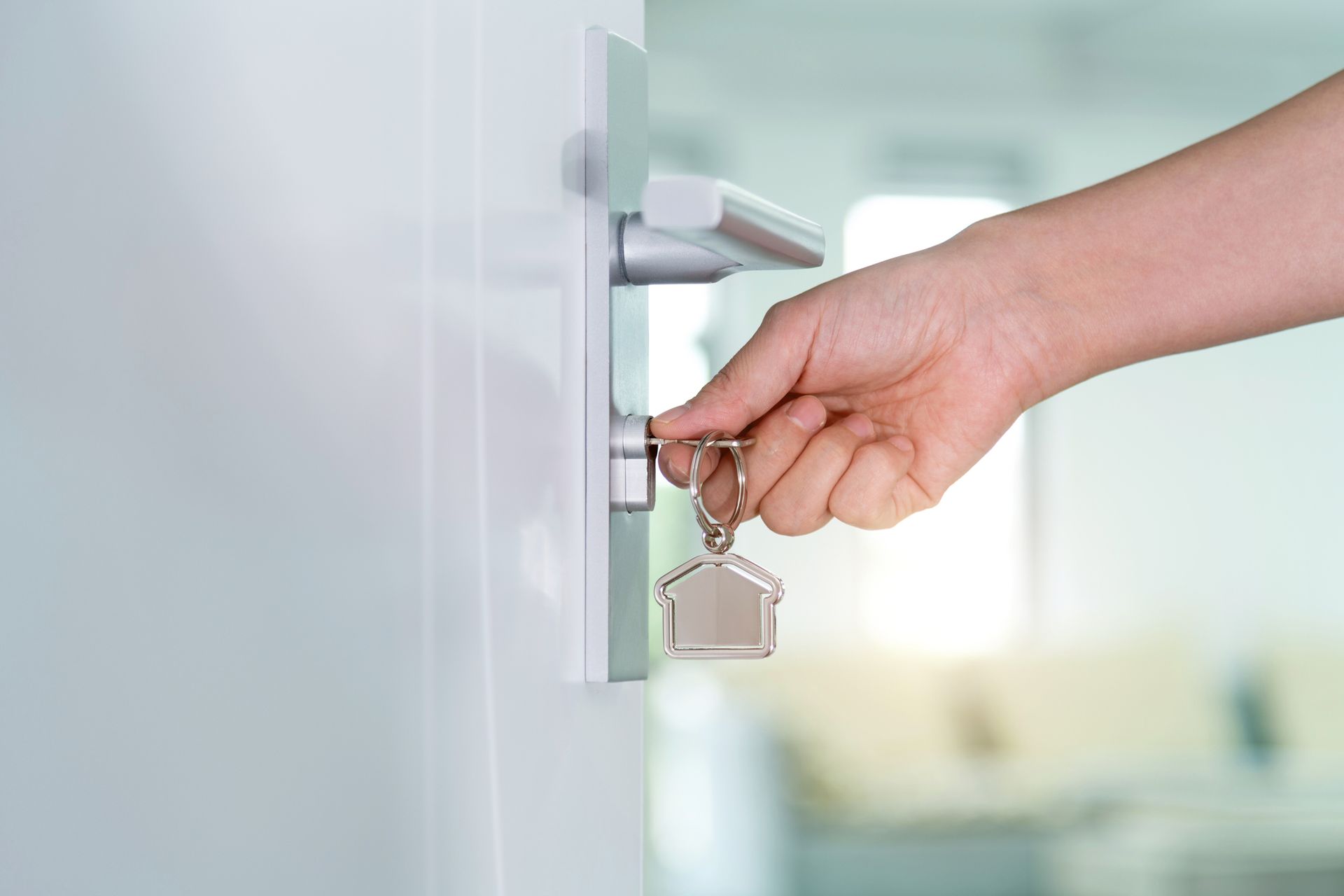 A person is holding a house key in their hand and opening a door.