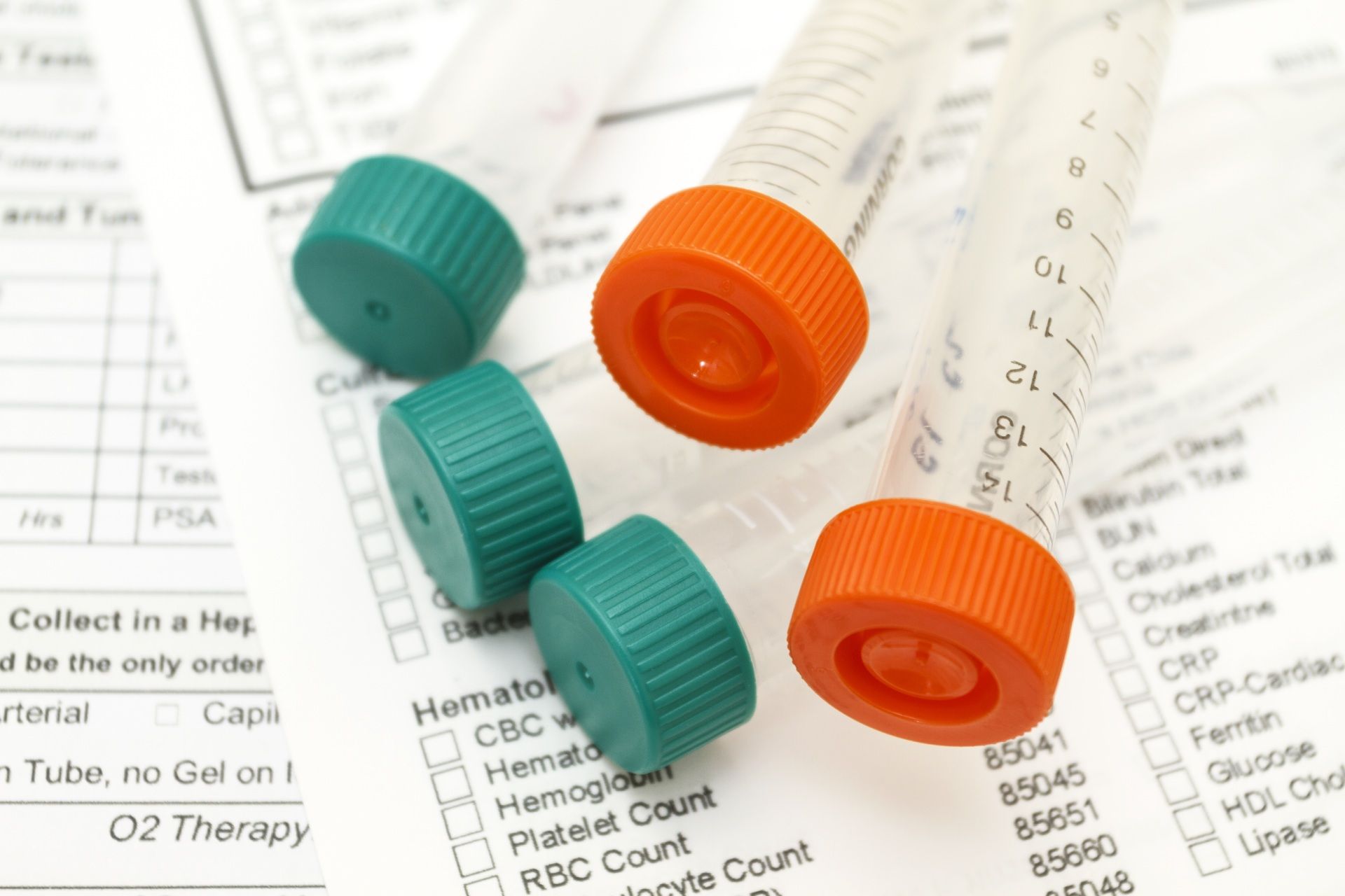 Blood collection tubes with green and orange caps on a lab form.