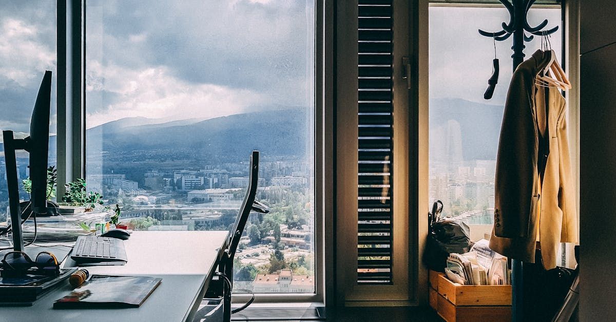 Une pièce avec une grande fenêtre et un bureau avec un ordinateur dessus.