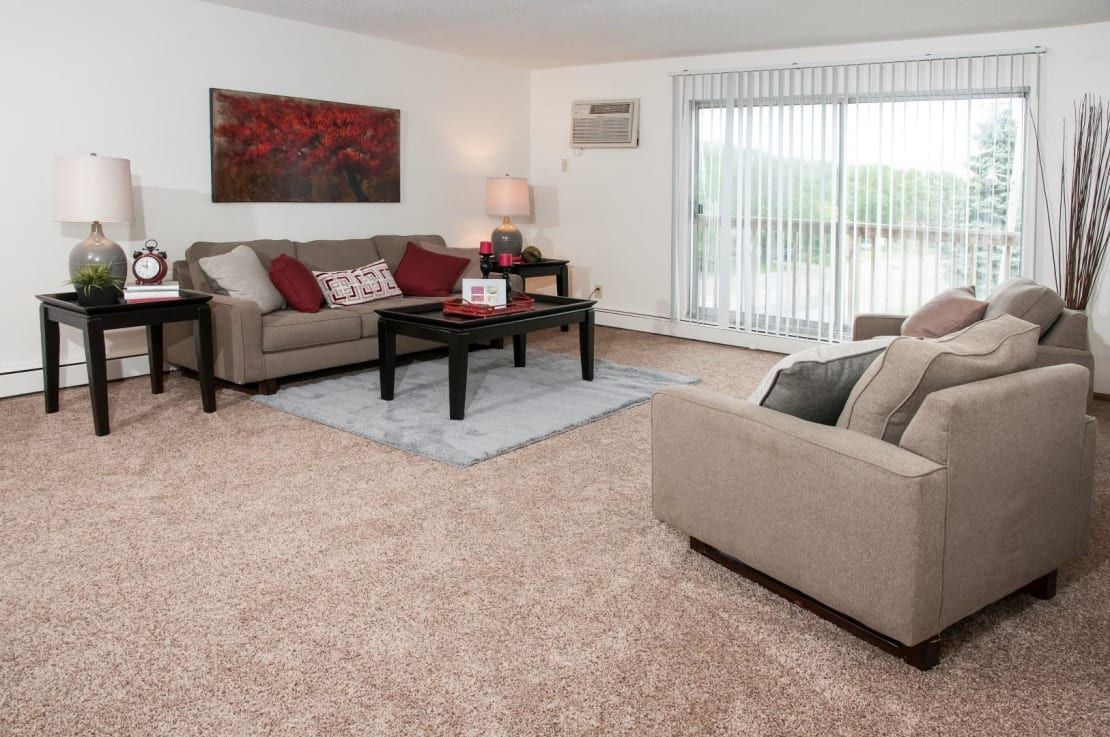 A living room with a couch , chair , coffee table and sliding glass doors.