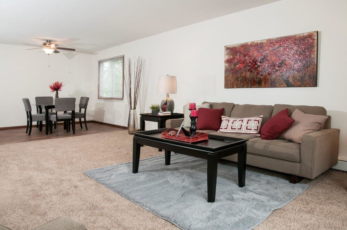 A living room with a couch , coffee table , dining table and chairs.