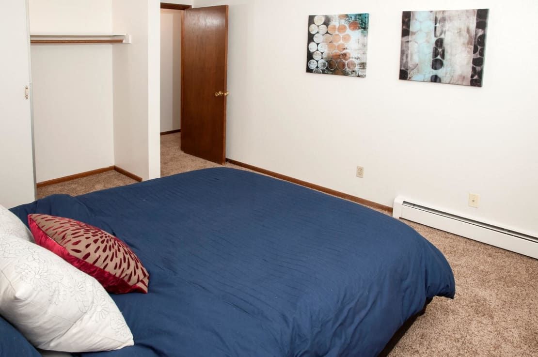 A bedroom with a large bed and two pictures on the wall