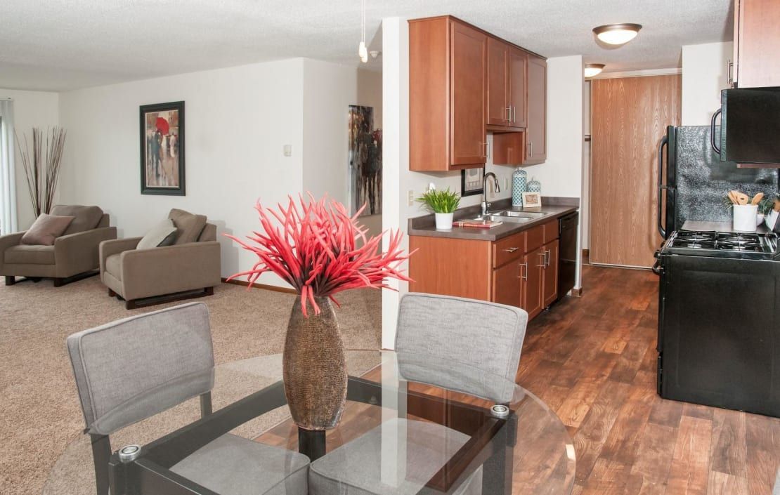 A living room with a dining table and chairs and a kitchen.