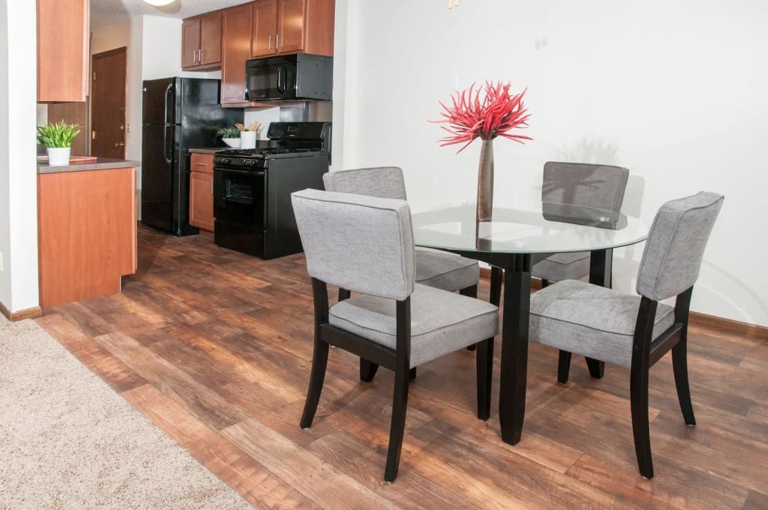 A dining room table and chairs in a kitchen with a vase of flowers on it.