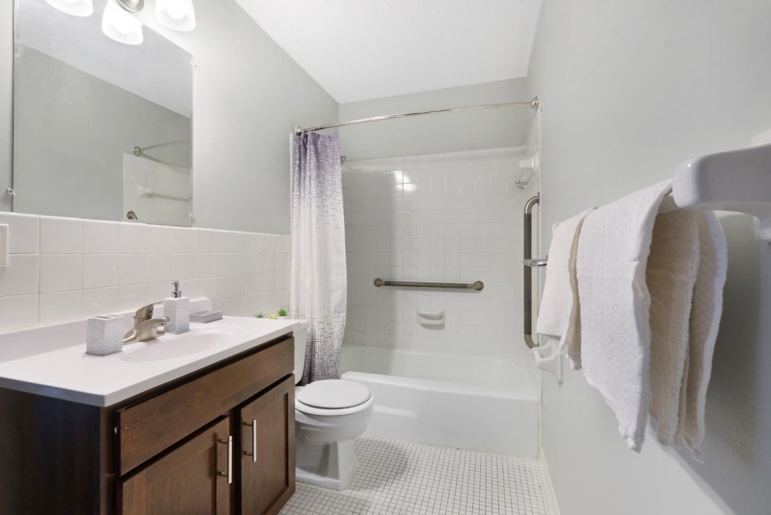A bathroom with a sink , toilet , bathtub and mirror.