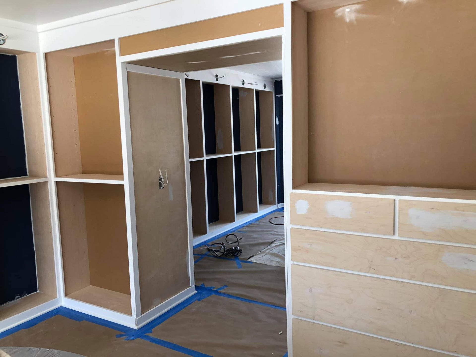Interior view of built-in shelving and cabinets with unfinished wood and white trim; construction site.