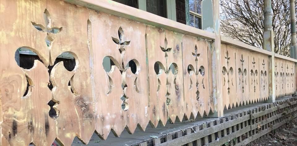 A room with recently sanded, light wood flooring, pale blue walls, white trim, and a metal radiator beneath a window.