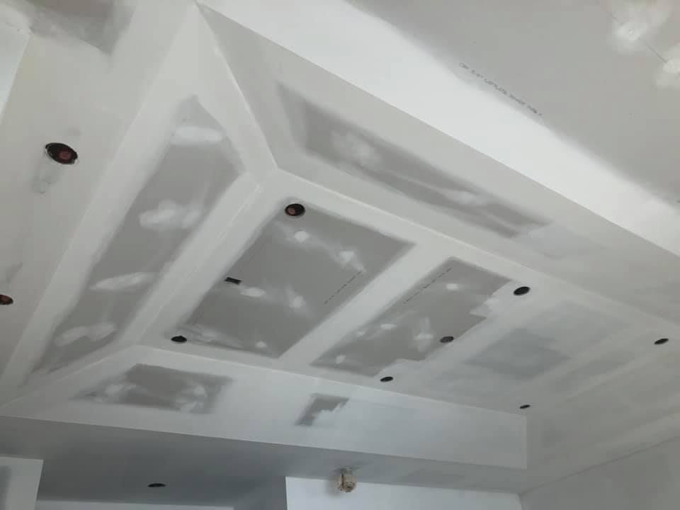 A partially finished drywall ceiling with taped seams and recessed lighting cutouts.