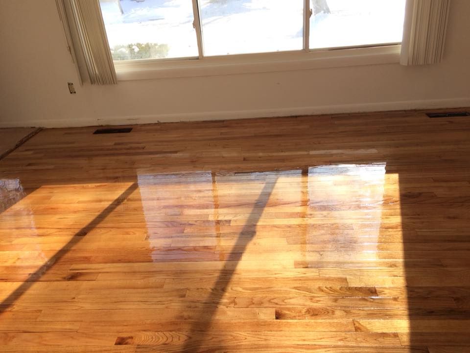 A modern kitchen featuring white cabinets, stainless steel appliances, light wood-look flooring, and a pantry cupboard.