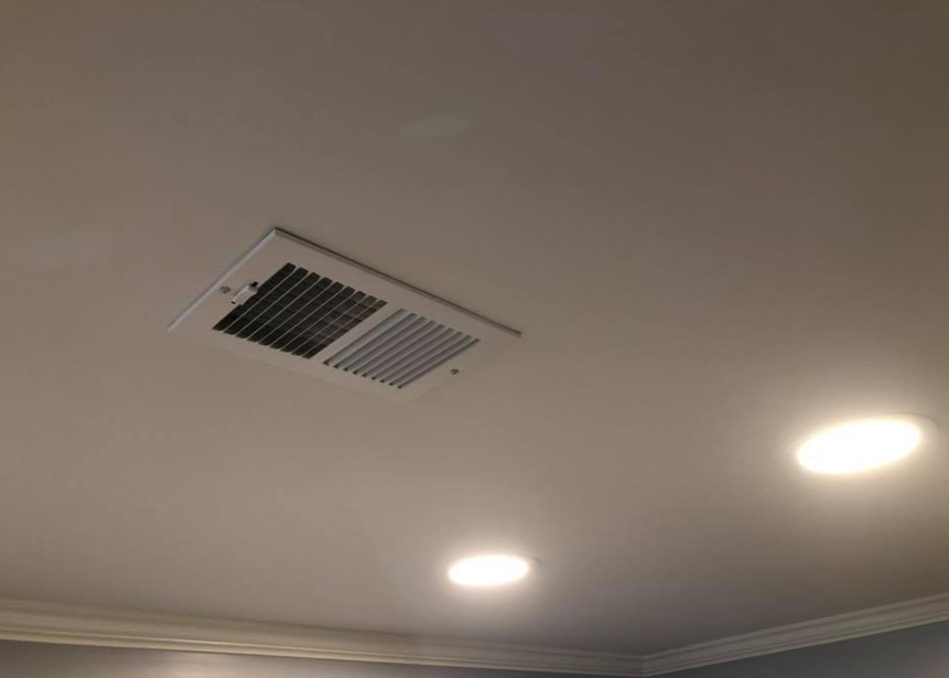 Blue house corner with white trim, green shutters, and windows overlooking a lake.