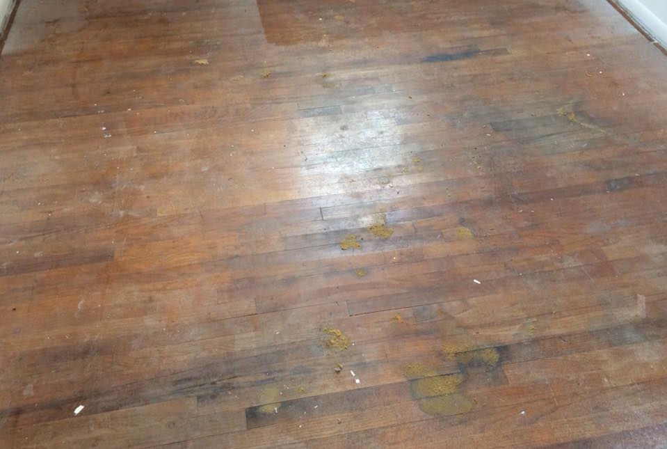 A black-and-white view of a basement workroom with a desk, shelving, storage items, and a tiled floor.