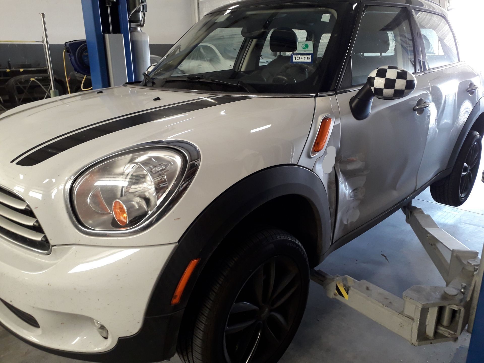 White Mini Cooper on a lift in an auto repair shop