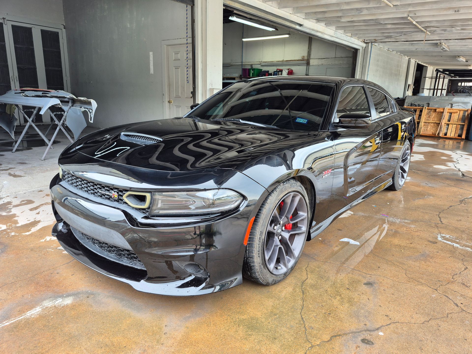 Black sports sedan parked in a garage, front-left view with glossy finish