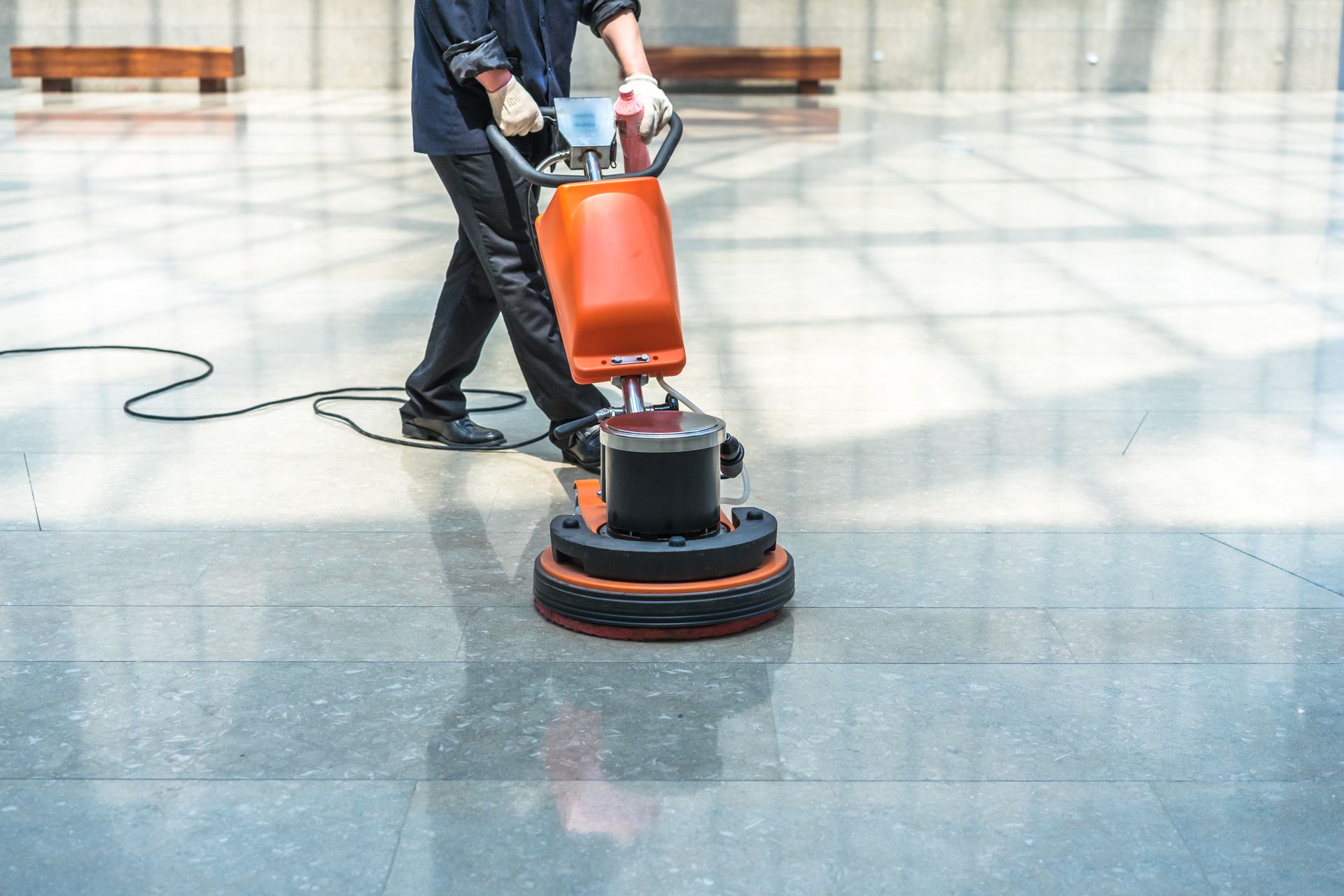 Person using a floor cleaning machine to efficiently scrub and polish the surface, leaving it sparkling clean and glossy.