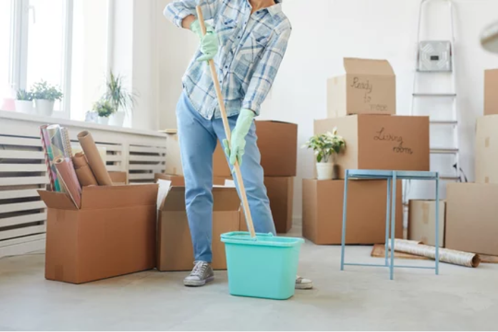 A woman enthusiastically cleaning and organizing her new house or apartment as she settles in after moving.