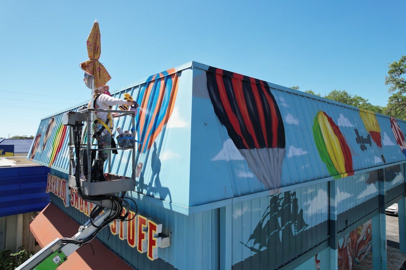 A man is painting a mural on the side of a building.