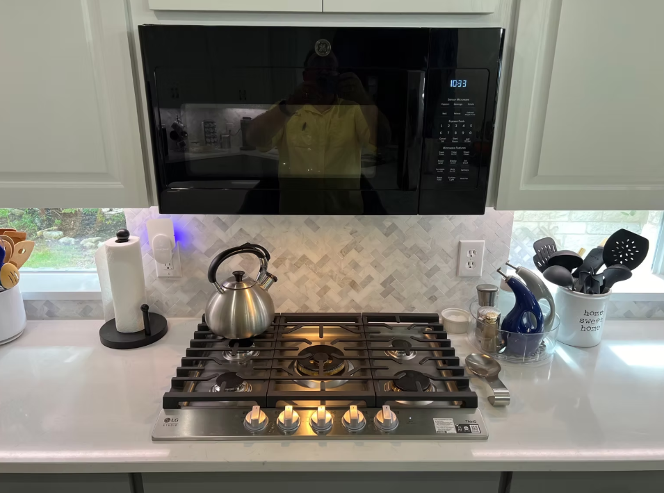 A stove top oven with a microwave above it in a kitchen.