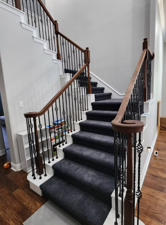 A staircase with a black carpet and a wooden railing.