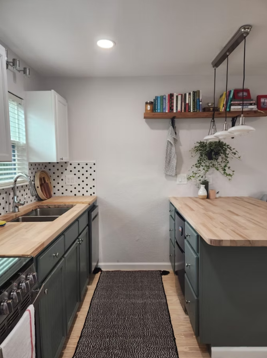 A kitchen with green cabinets and wooden counter tops