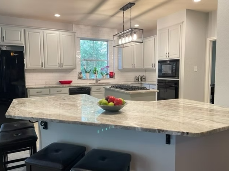A kitchen with a large island and a bowl of fruit on it.