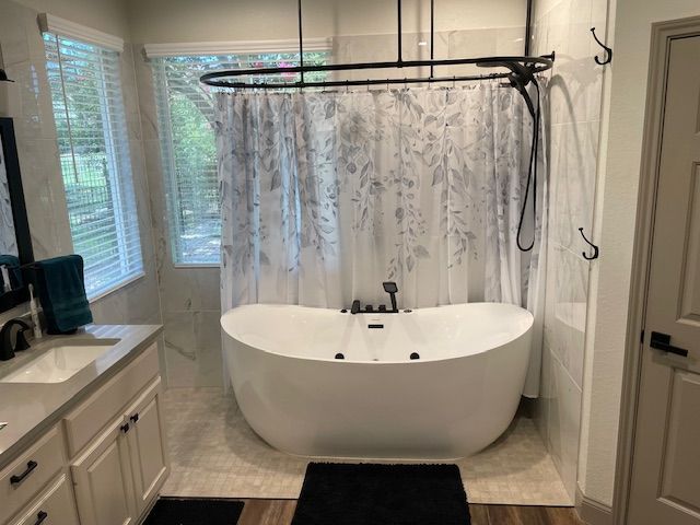 A bathroom with a bathtub , sink , and shower.