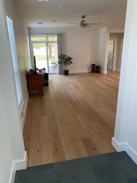 A living room with hardwood floors and a ceiling fan.