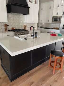 A kitchen with black cabinets and white counter tops