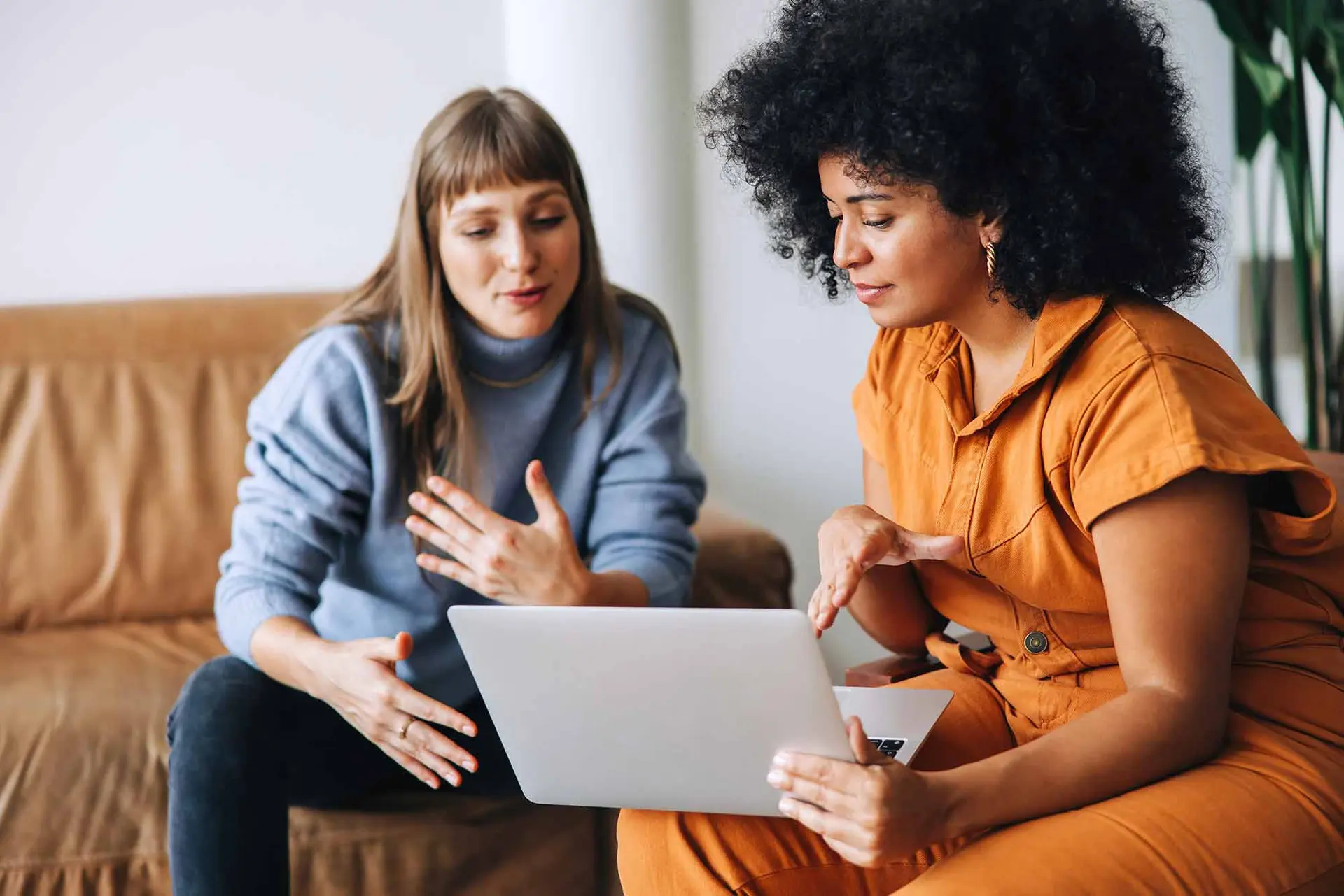 Two women having a conversation while looking at a laptop screen