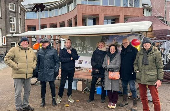 Een groep mensen staat voor een kar.