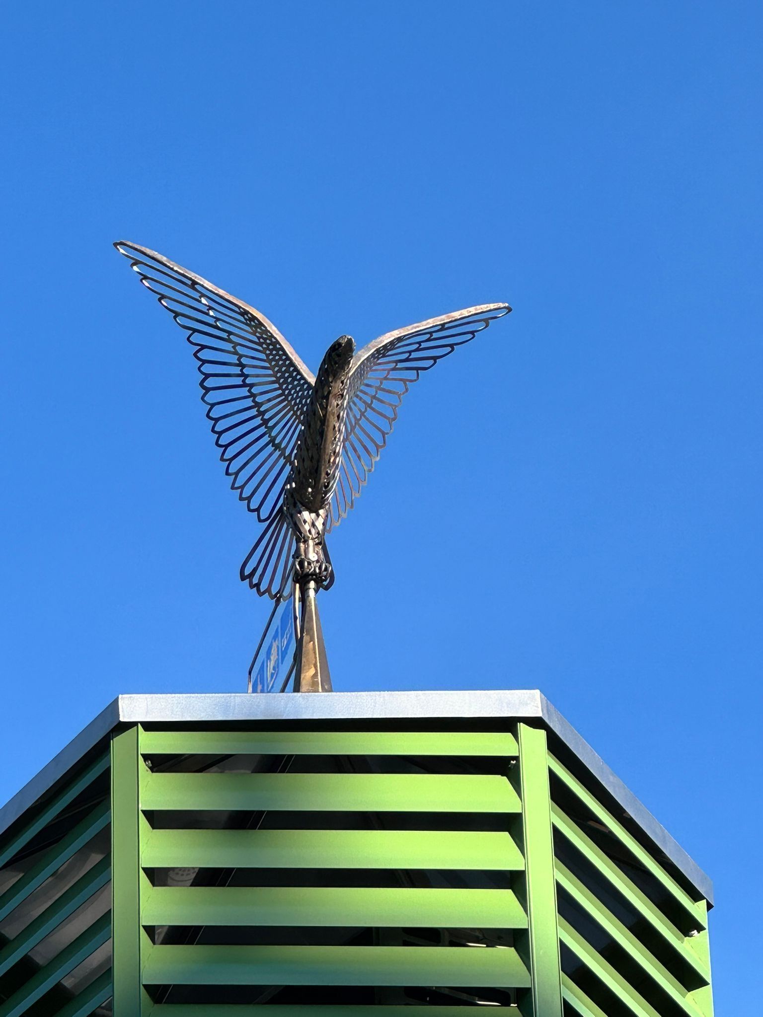 Een standbeeld van een vogel bovenop een groen gebouw