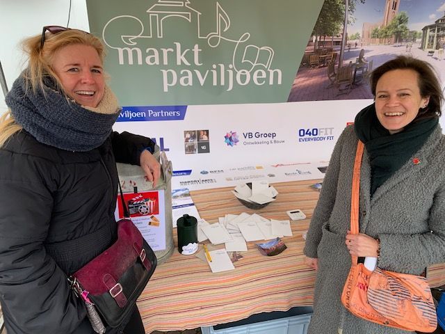 Twee vrouwen staan ​​voor een bord met de tekst marktpaviljoen