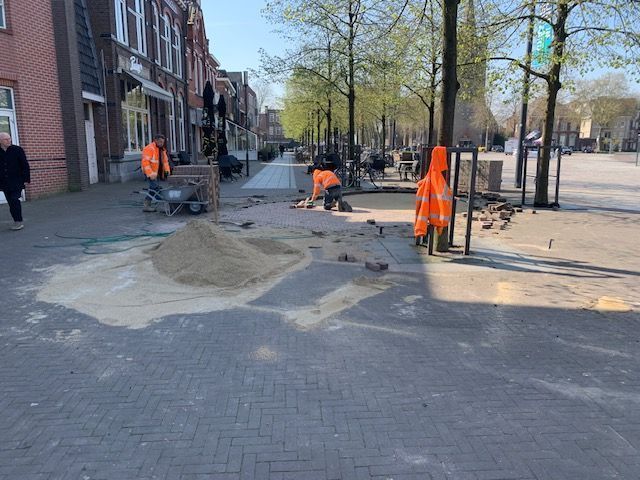Een groep bouwvakkers is bezig met het werk op een stoep.
