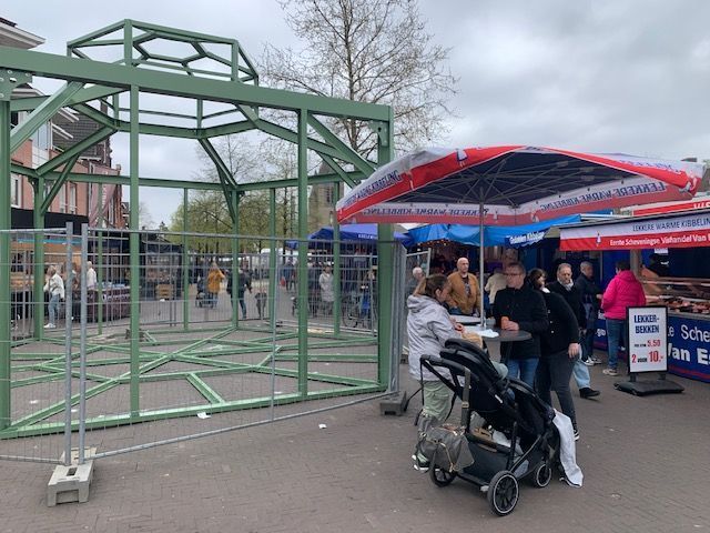 Een vrouw die een kinderwagen voor een hek op een markt duwt.