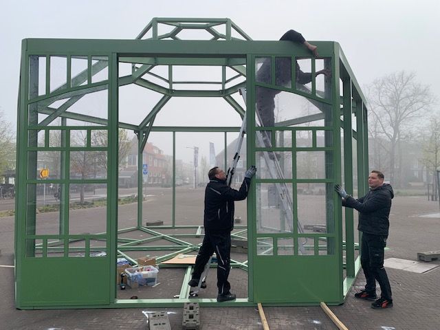 Een groep mannen werkt aan een kas.
