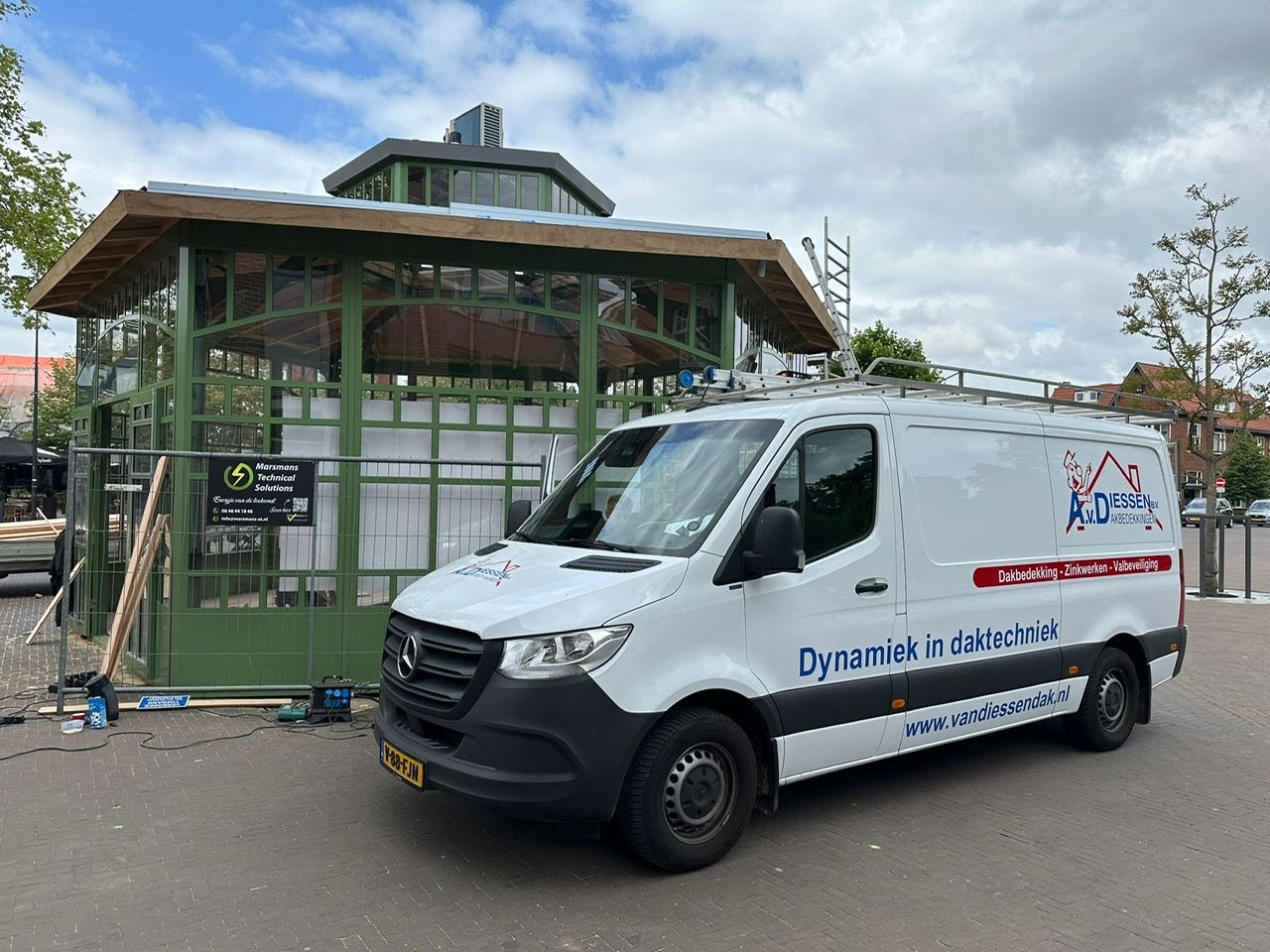 Een wit busje staat geparkeerd voor een gebouw in aanbouw.